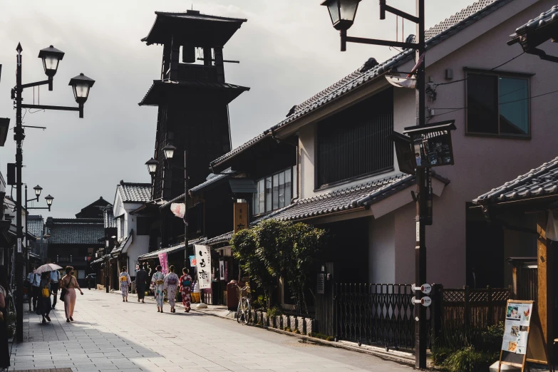 people are walking down an alley lined with street lamps