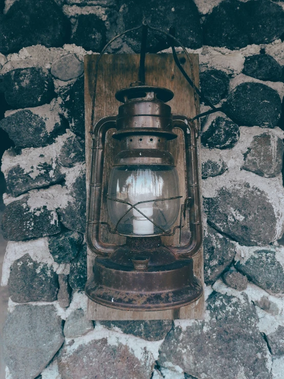 a lantern attached to a wall, hanging on the stone wall