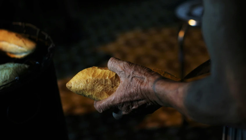 a person holding bread in their hand with both hands