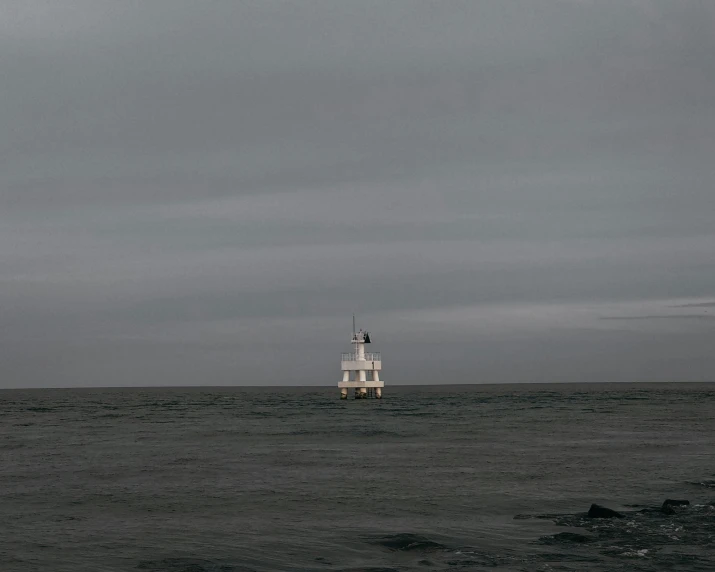 the lighthouse is near the ocean in the cloudy sky