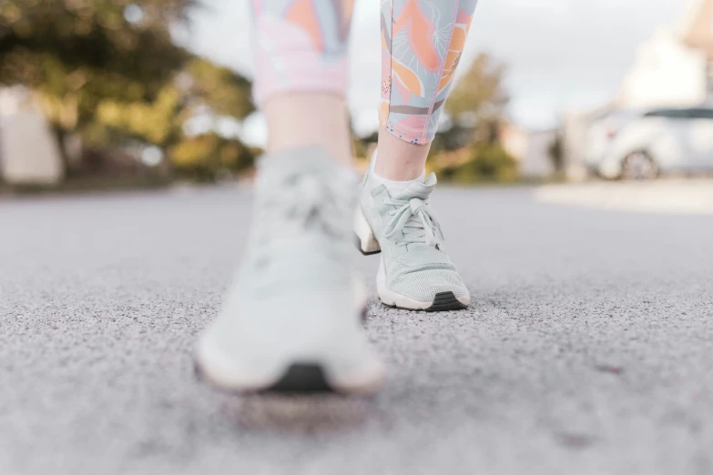 a woman's feet in sneakers walking along the street