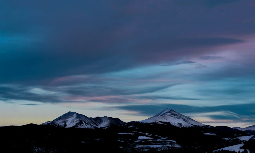 a large mountain range covered in snow and some clouds