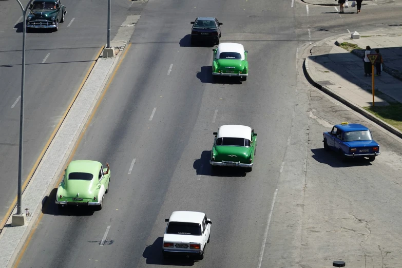 many old cars are traveling down an empty street