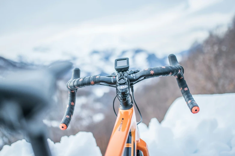 an orange bicycle on a snowy mountain with an orange bar