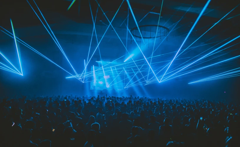 a large room full of people that are dancing in front of light beams