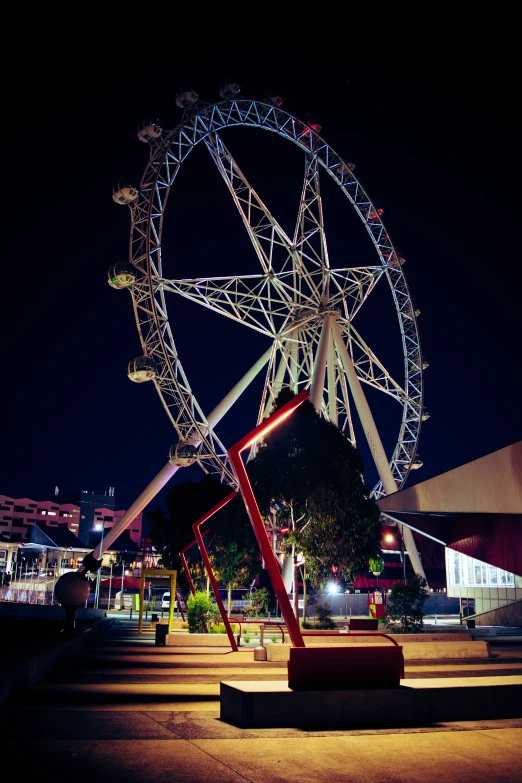 there is a ferris wheel at night near the parking lot