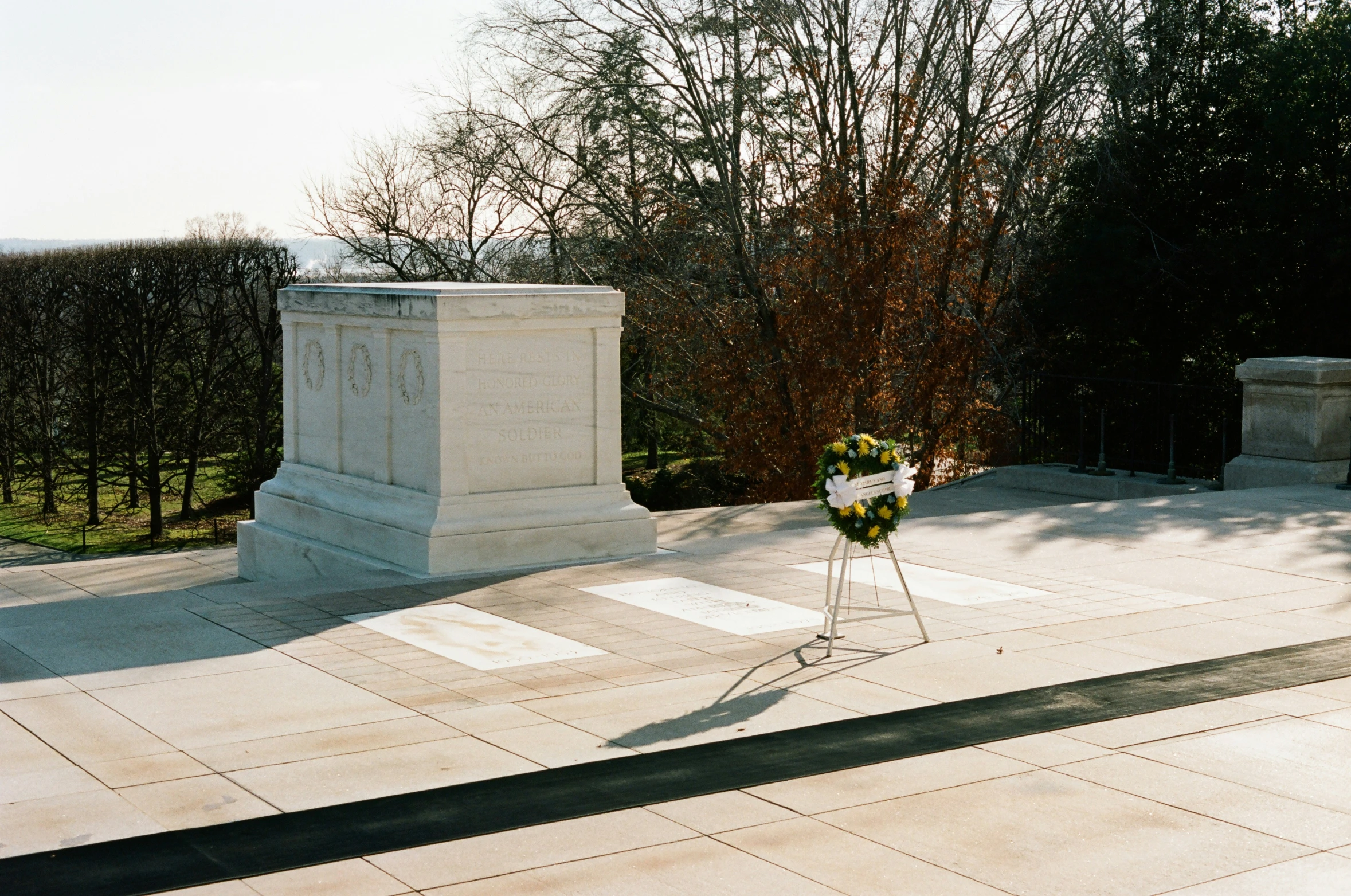 a white monument and trees at the end of the walk