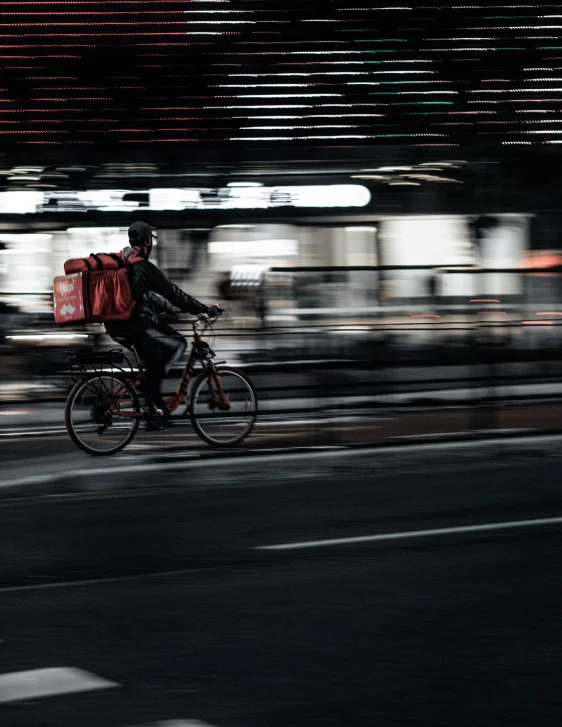 a person riding a bicycle down a street with luggage on his back