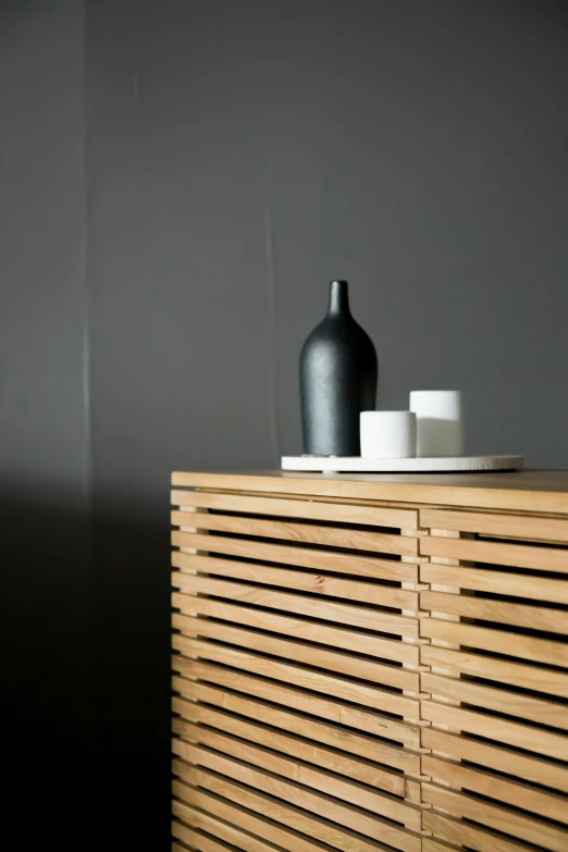 a black vase sitting on top of a wooden chest of drawers