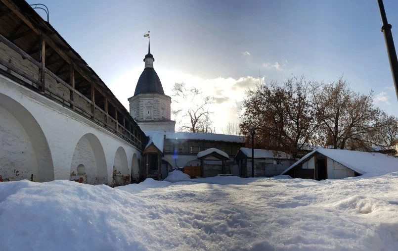 a snowy hill with buildings and a white clock tower in the distance