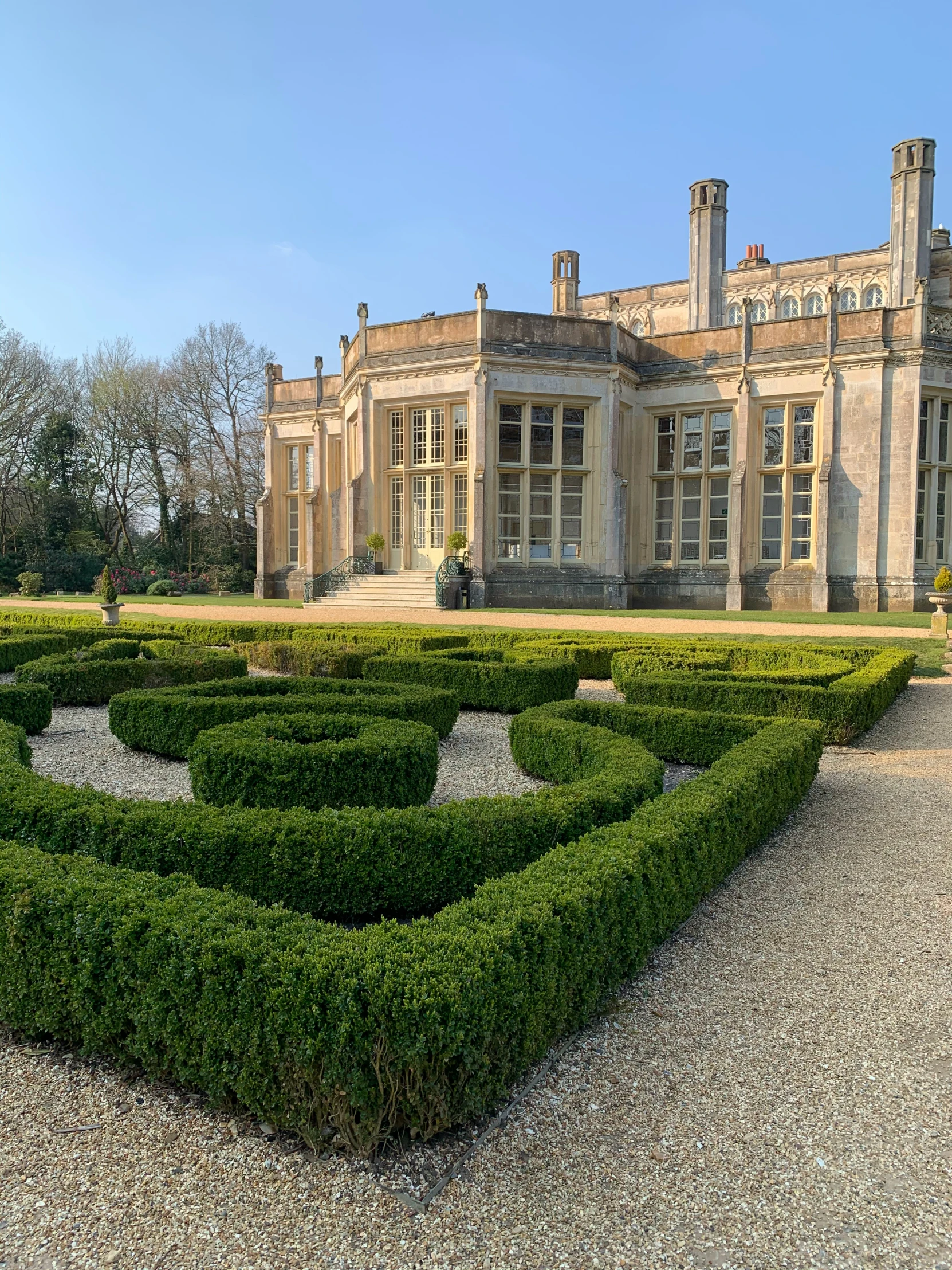 a large building with a hedges in the foreground