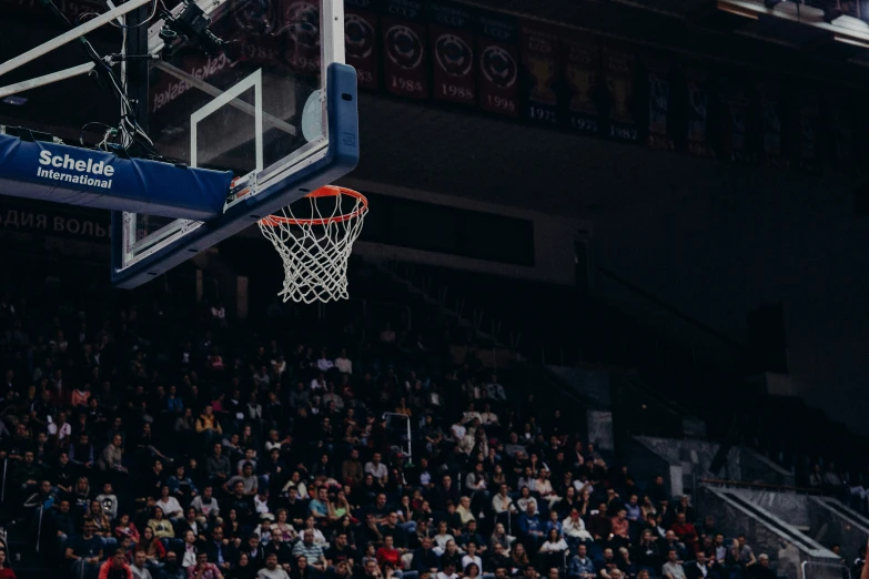 a basketball net is being pulled down and hangs above a crowd of people