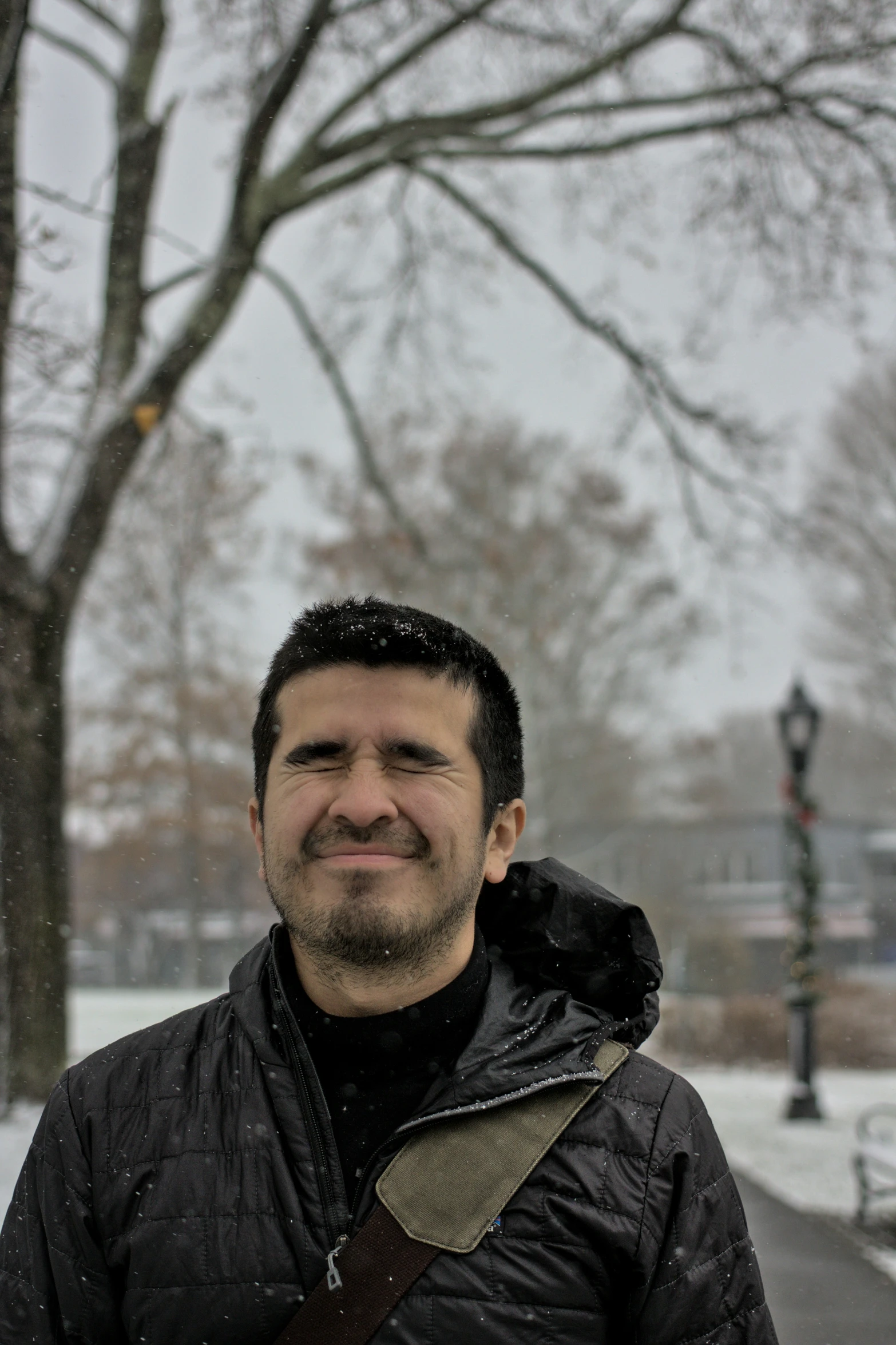 a man wearing a jacket standing by the snow covered road