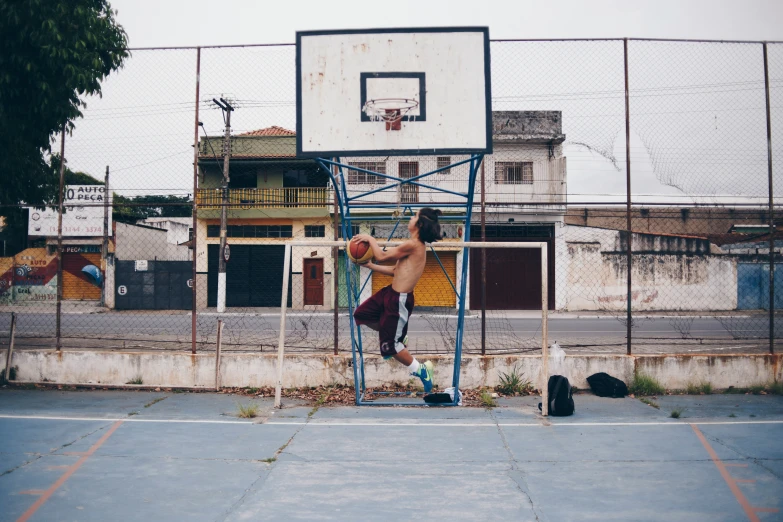 a shirtless man standing in front of a basketball hoop