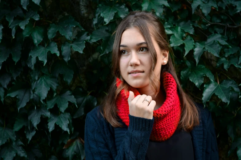 a woman stands in front of ivy covered bushes