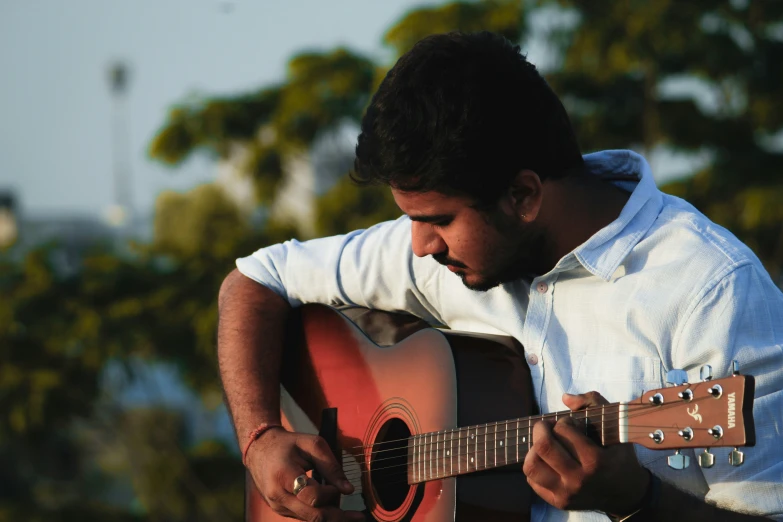 a man playing a red acoustic guitar outside
