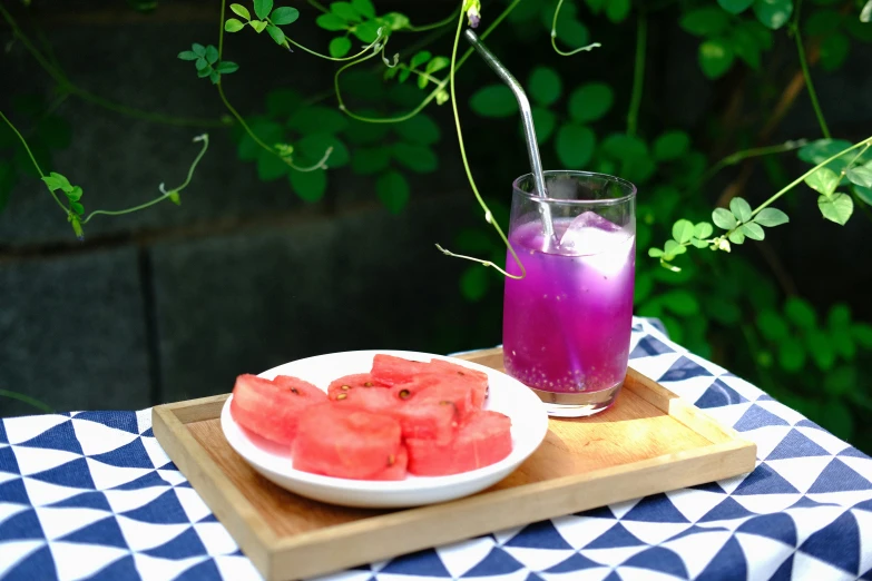 a plate of tomato on a tray next to purple and blue drink