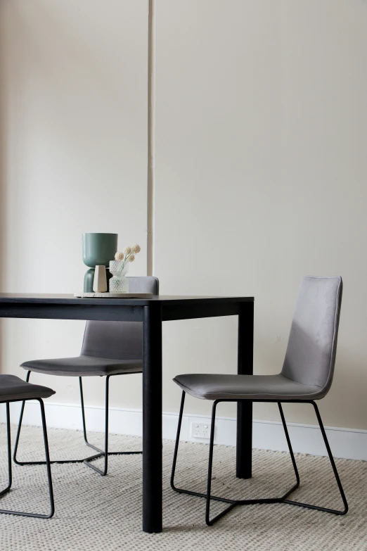 two dining chairs sitting under a table next to an empty vase