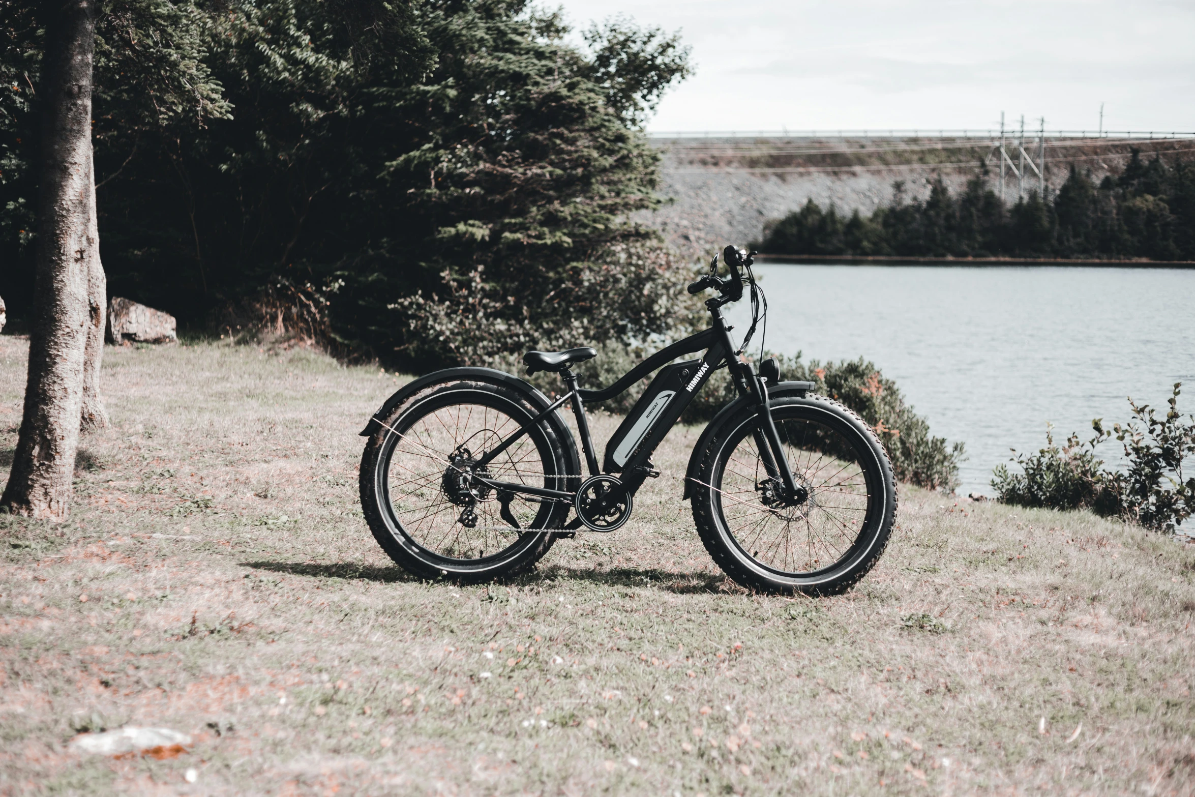 a single bicycle parked on the edge of some grass by a river