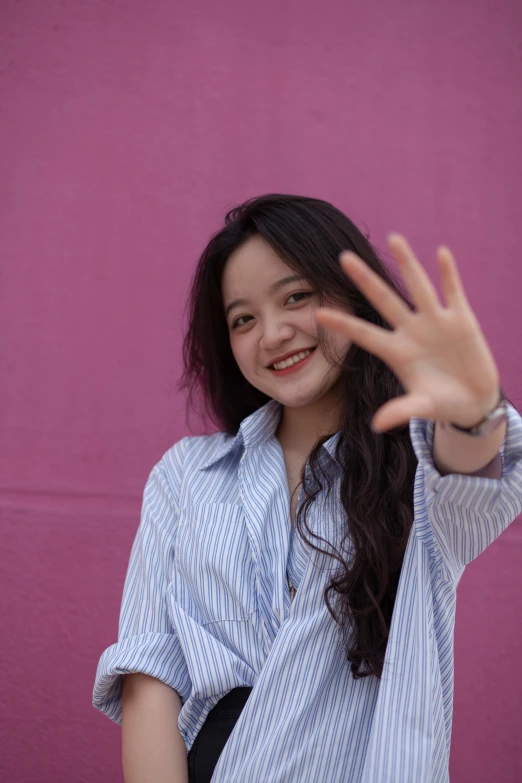 a young woman making the letter's hand sign with her left hand