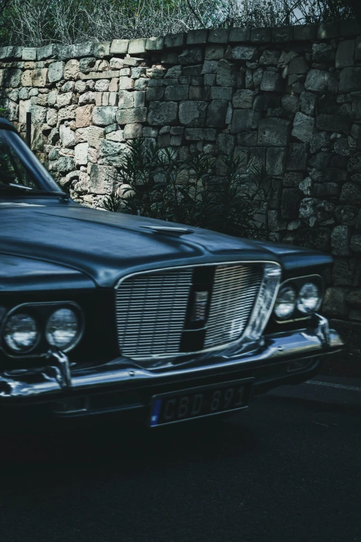 an older fashioned car is parked outside near a brick wall