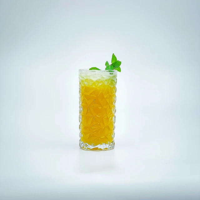 a glass with orange juice and a mint