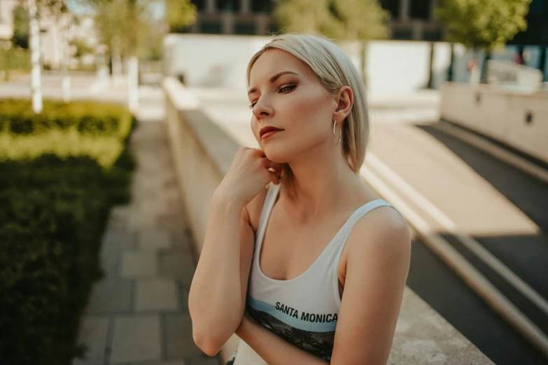 woman leaning against ledge next to plant and sidewalk