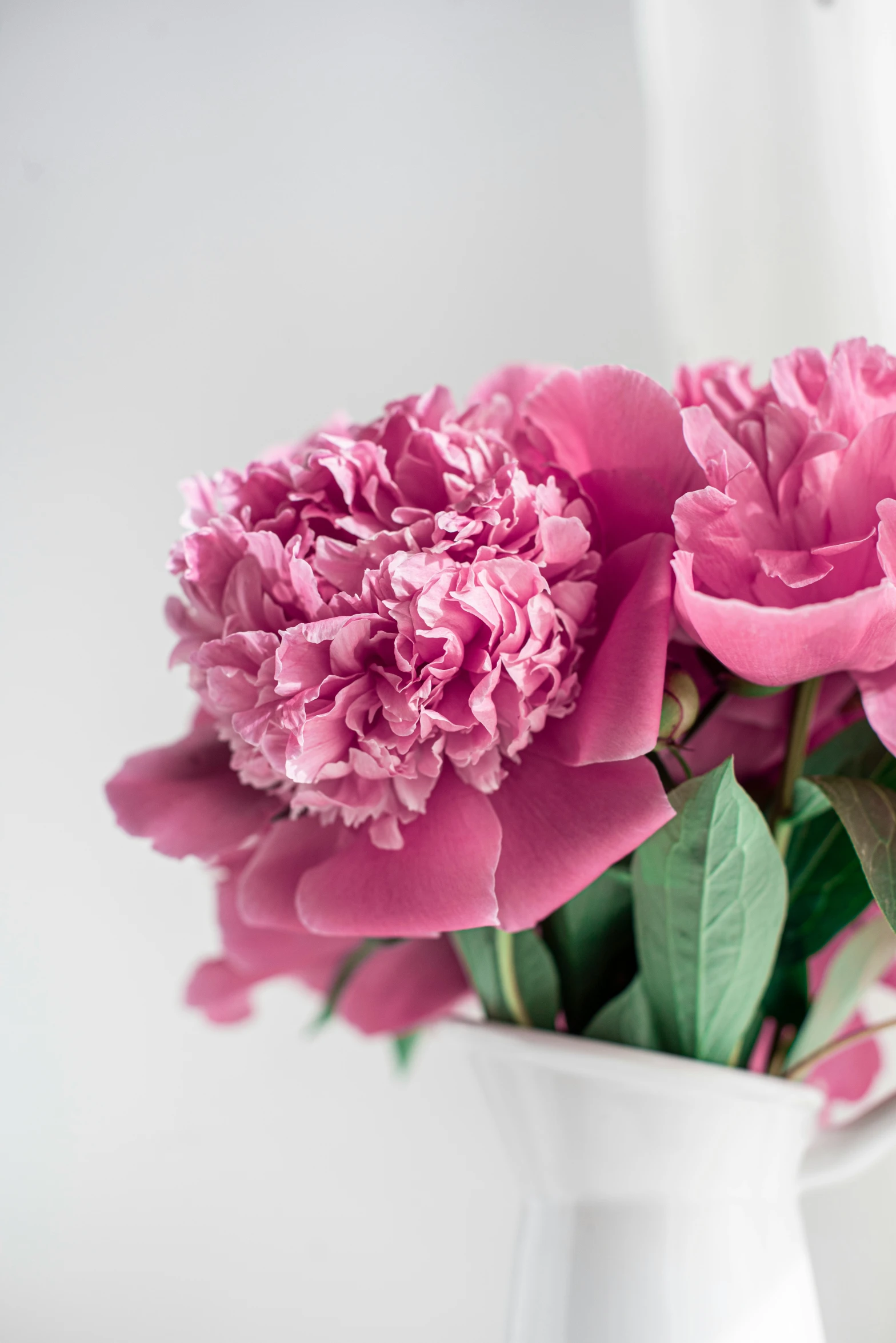 some flowers in a white vase are sitting next to a window