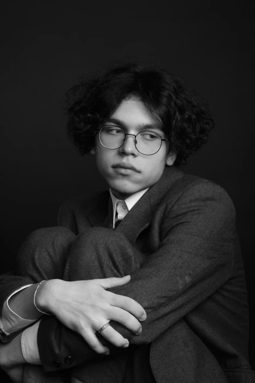 a young man sitting in a chair wearing glasses