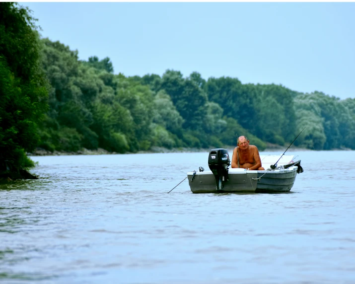 man on the back of small boat with poles