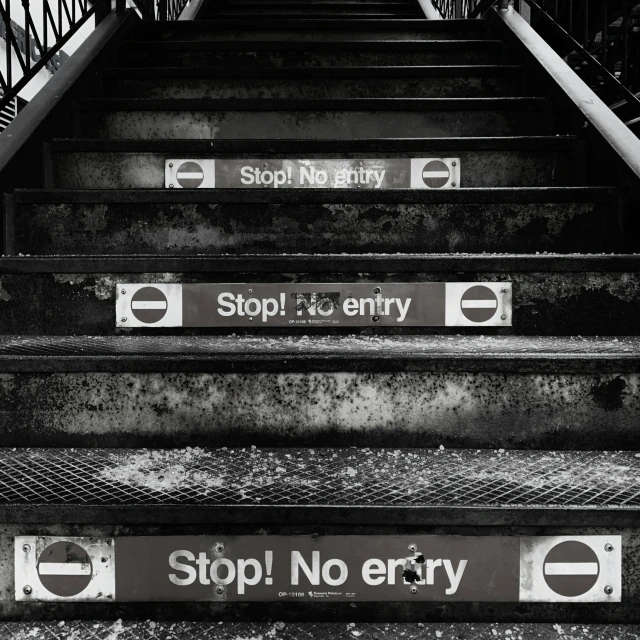 black and white picture of stairs with signs indicating no entry