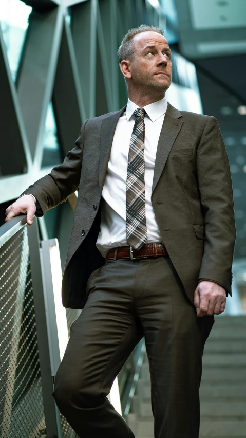 a man wearing a suit and tie leaning on some stairs