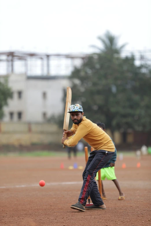 a man holding a bat up to hit a baseball