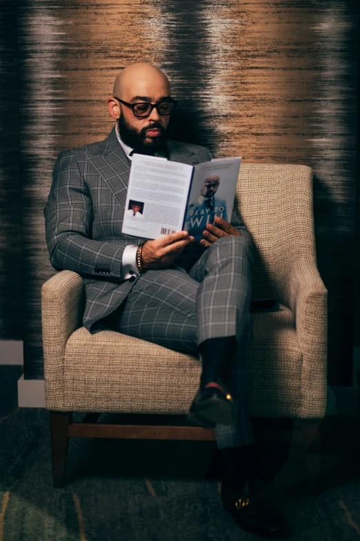 a man sitting down holding his laptop with a book