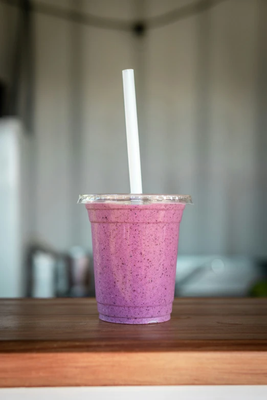 a smoothie topped with two straws in a pink plastic cup