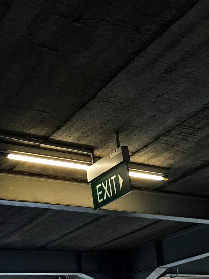 exit sign hanging underneath an elevated road overpass