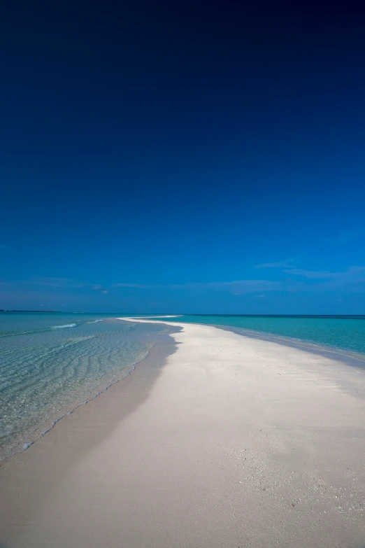 an empty beach surrounded by the ocean on a clear day