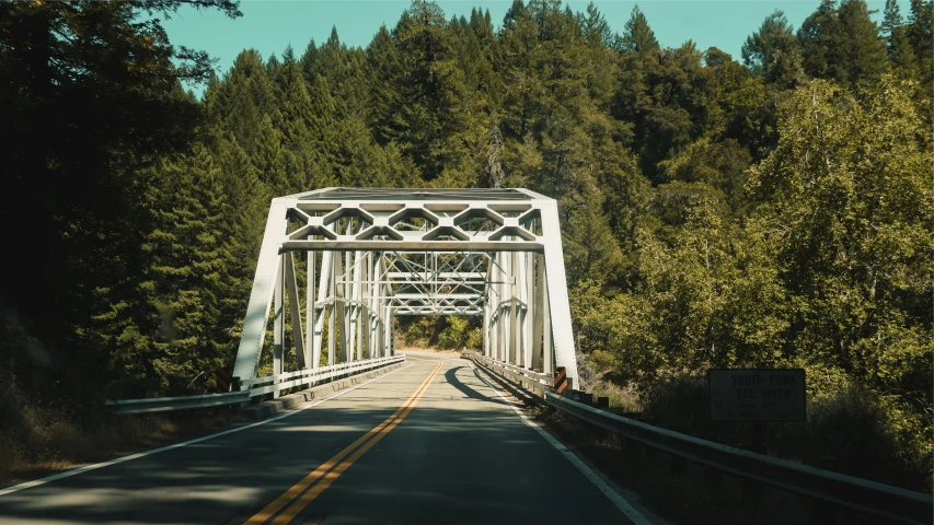 an old white train trestle is on the road