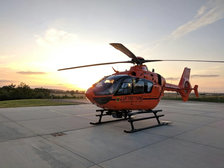 a helicopter sits on the ground at sunset