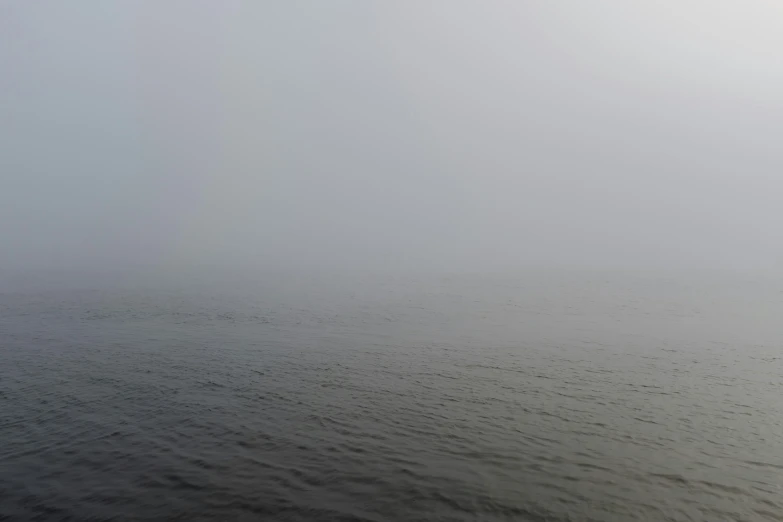 lone sail boat on open ocean in foggy weather