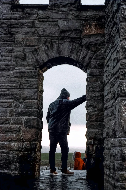 an image of man in the rain under an archway