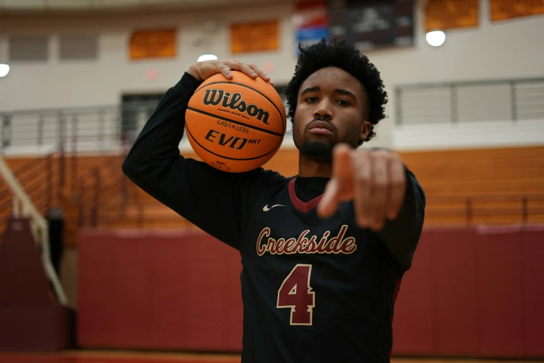 a man holding a basketball while pointing to it