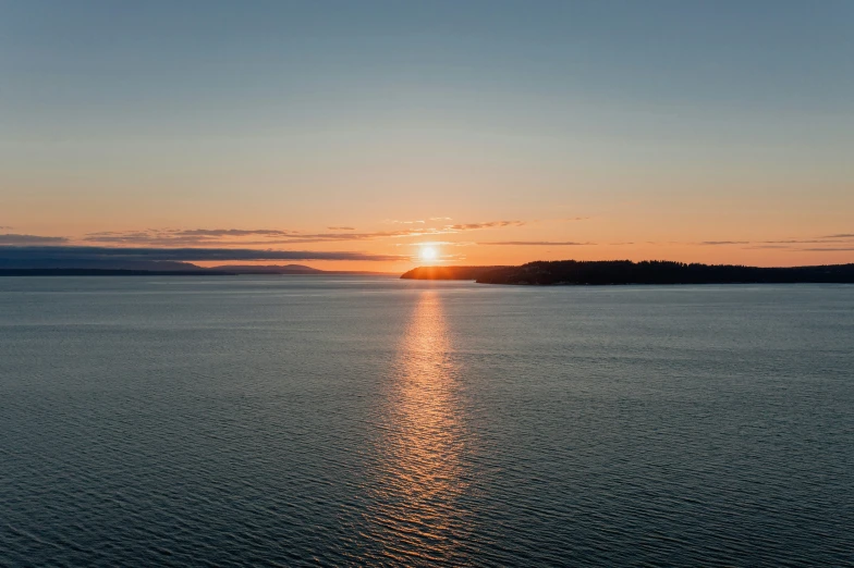 a long line of water with the sun going down in the background