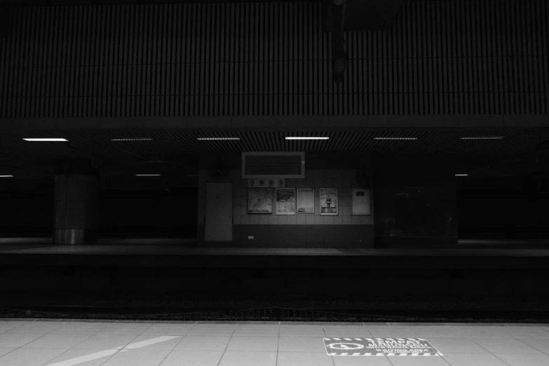 black and white pograph of a sign sitting in front of an empty train station