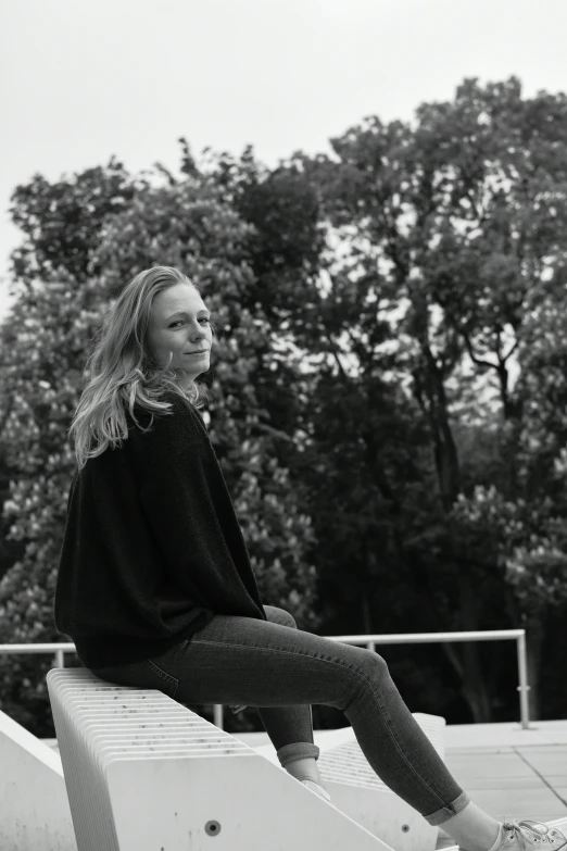 a black and white image of a woman sitting on a bench