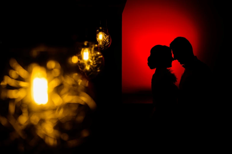 two people standing together and illuminated by lights