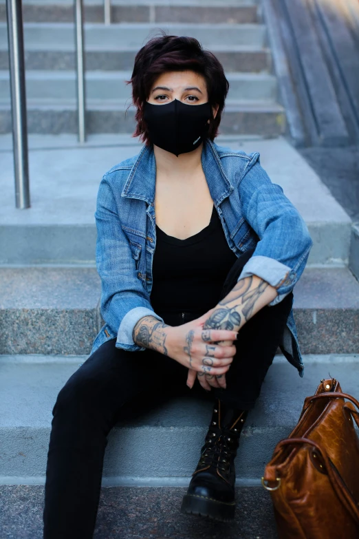 a woman in a face mask sitting on the steps of an staircase