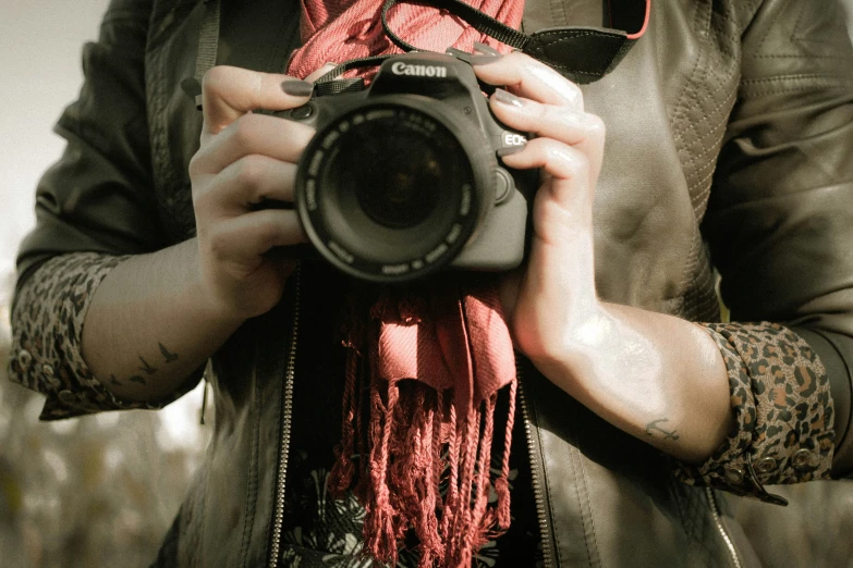 a person with tattoos on their arms is holding a camera