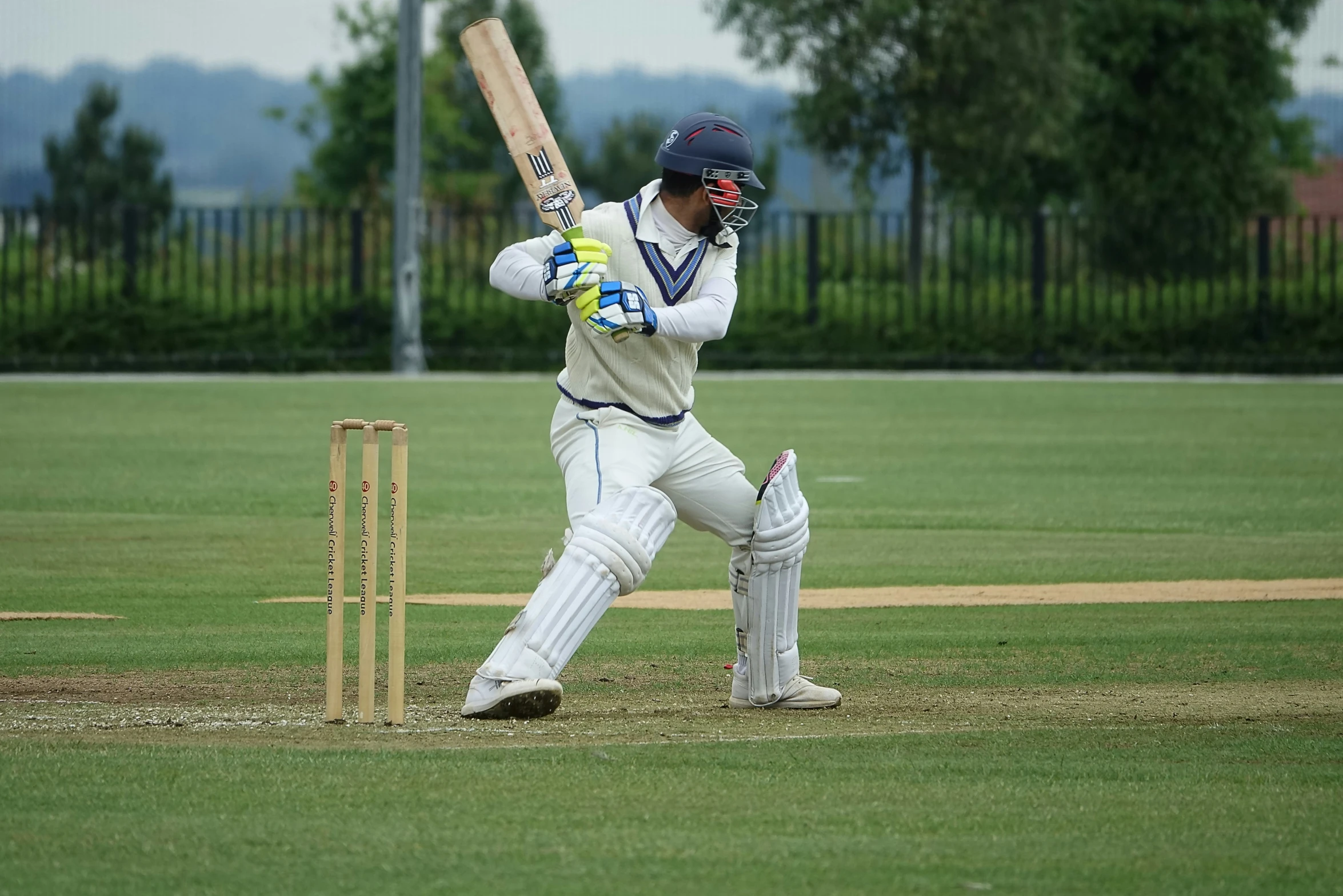 there is a male playing cricket on the field