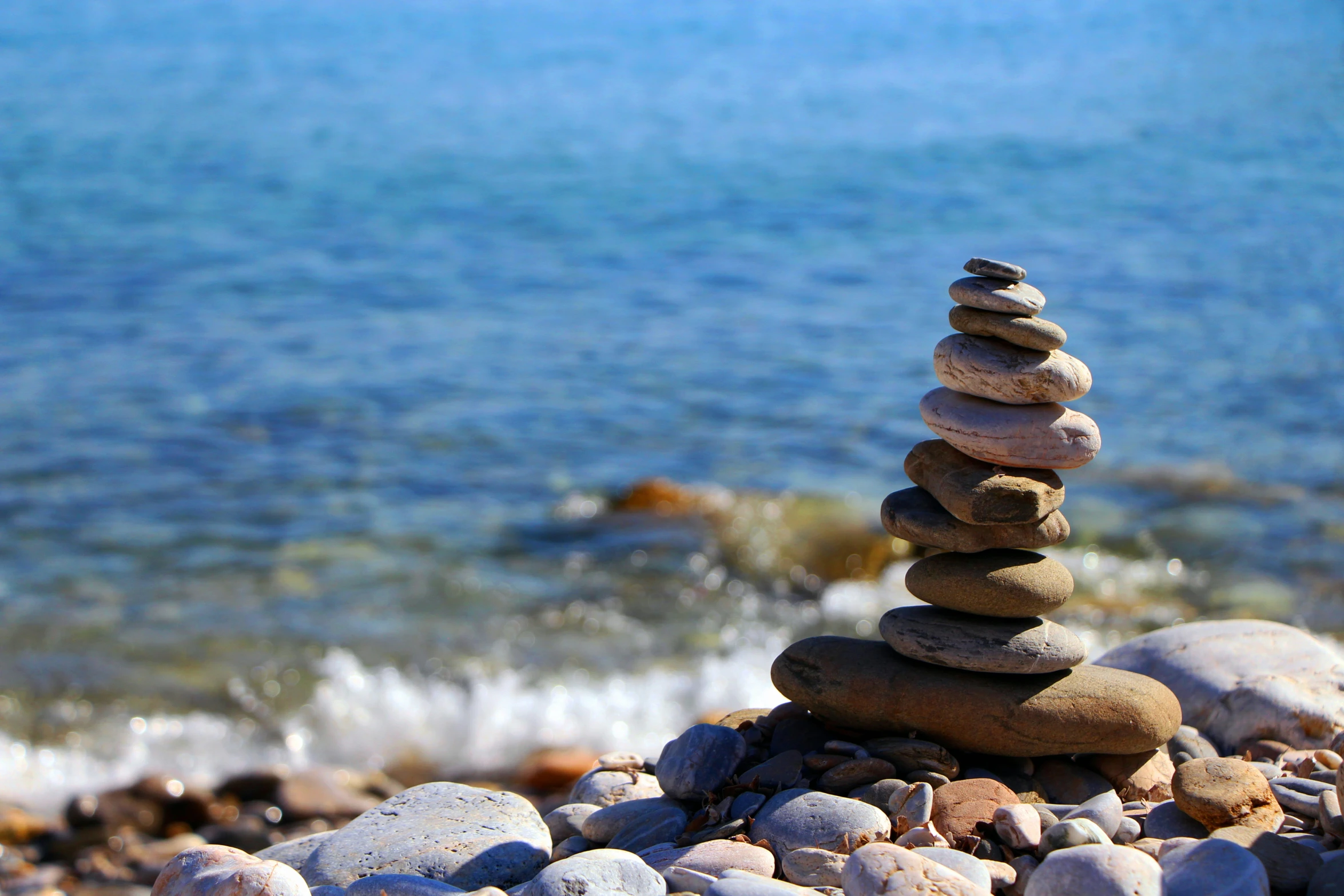 a stack of stones sitting on top of a pile of rocks next to the ocean